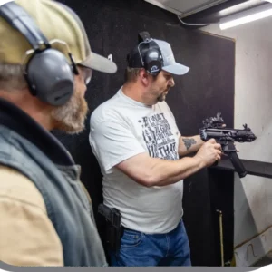 Two men are holding guns in a gun range.