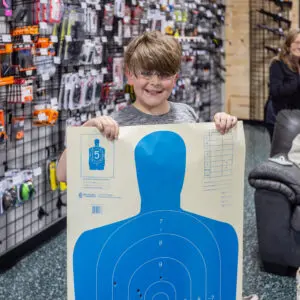 A boy holding up a blue target in front of his face.