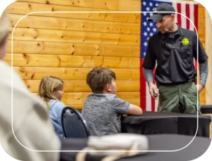 A man in an american flag shirt talking to two children.