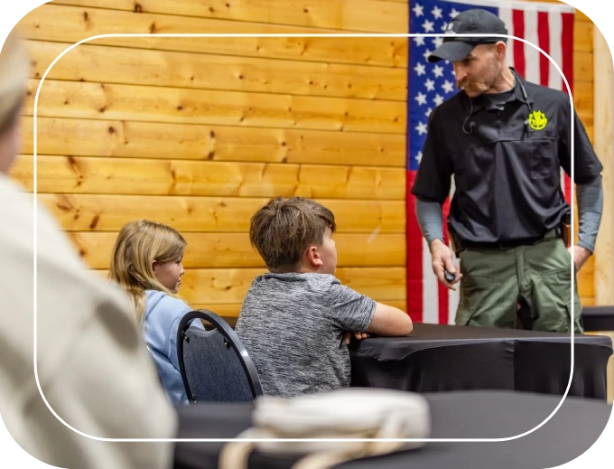 A man in an american flag shirt talking to two children.